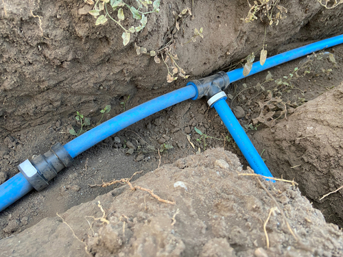 Photograph of blue irrigation pipe in a trench