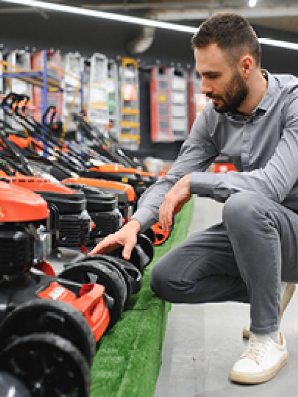 Man looking at lawnmowers in a store